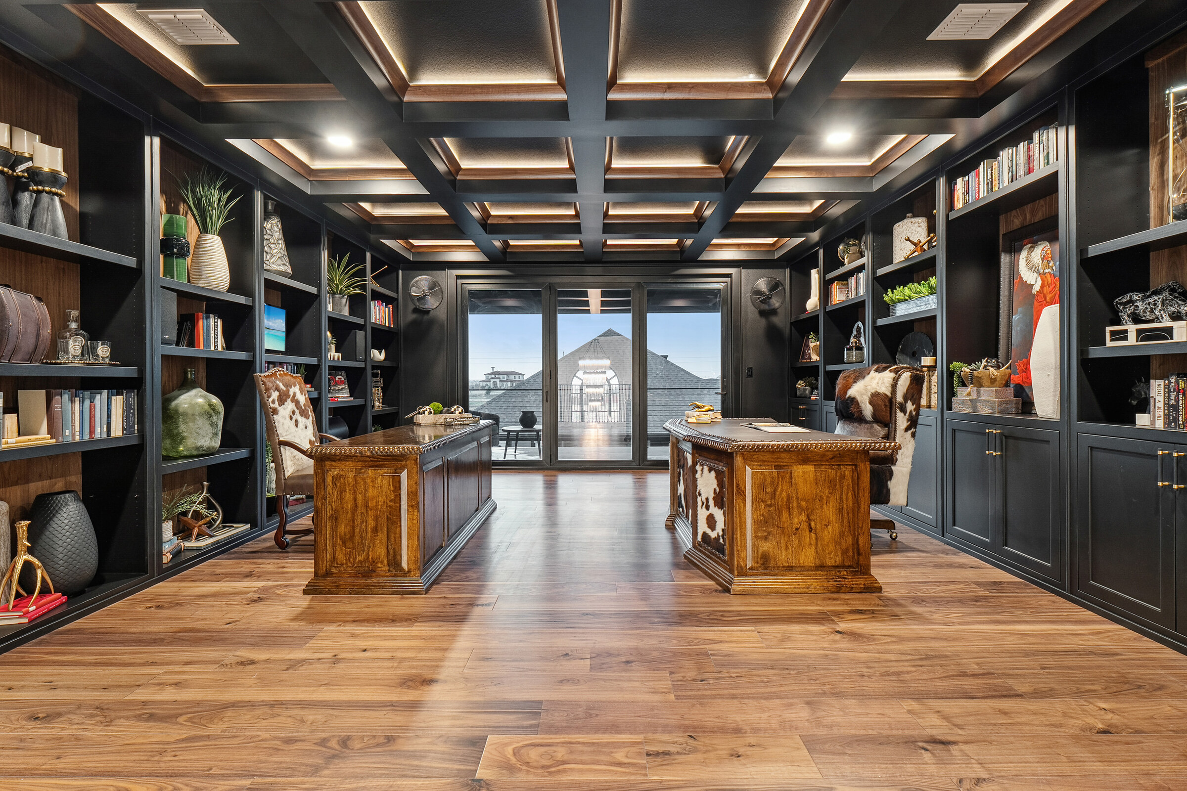 High-resolution real photograph of a luxury home library with illuminated coffered ceiling and full-height built-in bookcases