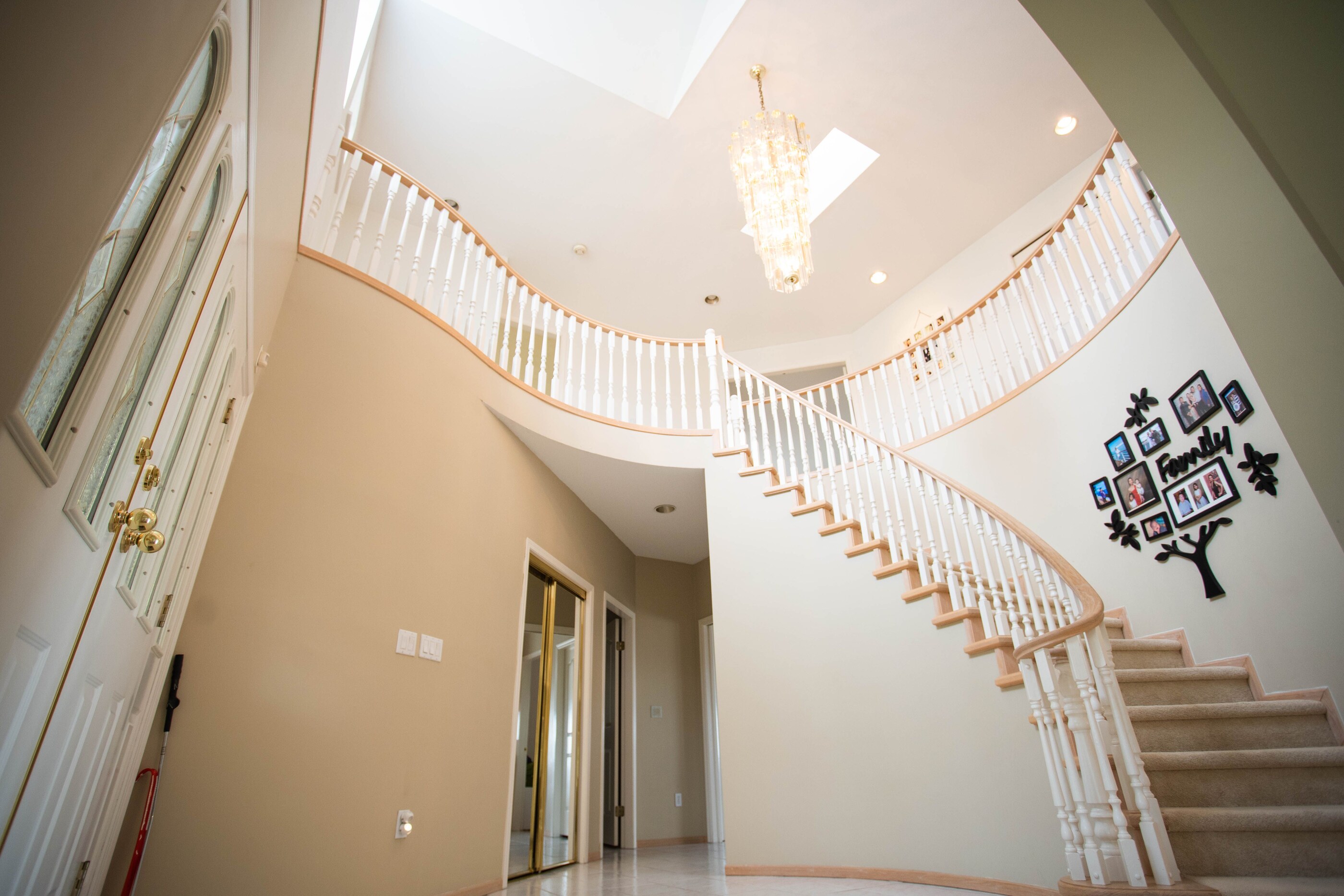 High-resolution real photograph of a curved staircase with white balusters and a warm stained wood handrail